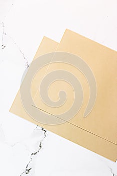 Beige A4 papers on white marble background as office stationery flatlay, luxury branding flat lay and brand identity