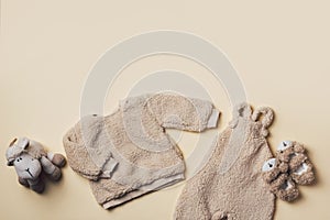 Beige baby teddy bodysuit, sweatshirt, soft toy sheep on pastel backgroundd. Styled newborn clothes. Copy space. Flat