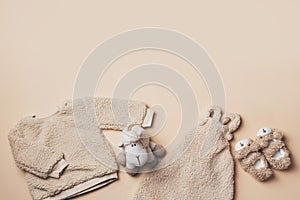 Beige baby teddy bodysuit, sweatshirt, soft toy sheep on pastel backgroundd. Styled newborn clothes. Copy space. Flat