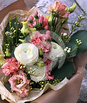 Beige bouquet. Pink roses, white Ranunnculus, pink eustoma and white Chamelauciumin a bouquet of fresh flowers on a light
