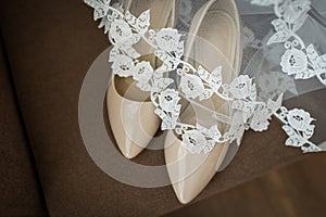 Beige bridal shoes are covered with a veil.