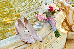 Beige bride`s shoes standing near fresh wedding bouquet