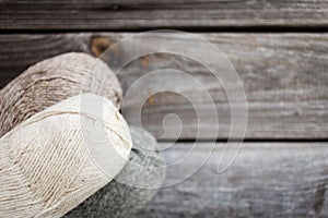 Beige, brown, gray and white balls of yarn. Wooden background