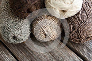 Beige, brown, gray and white balls of yarn. Wooden background