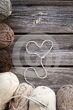 Beige, brown, gray and white balls of yarn. Wooden background