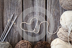 Beige, brown, gray and white balls of yarn. Wooden background