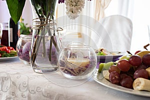 Beige candle in a glass vase with lilac petals. Wedding decor on the table at the newlyweds