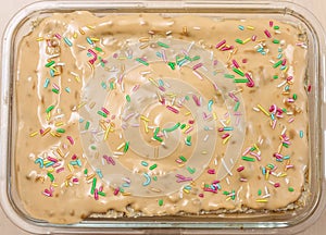 beige caramel cake with colorful sprinkles. background