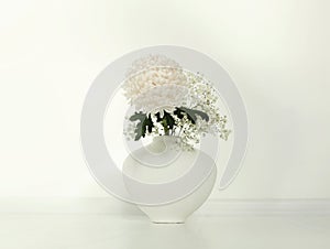 Beige chrysanthemums flower in vase on white interior. Minimalist still life. Light horizontal background