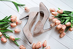 Beige color nude women shoes with flowers on white wood background top view