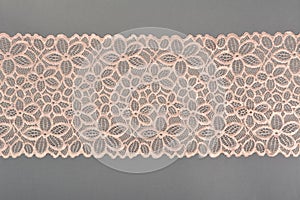 Color straight strip of lace fabric on a gray background. Elastic silk nylon braid border. use for clothes and linen decoration