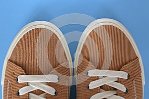 Beige corduroy sneakers on a blue background