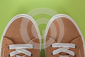 Beige corduroy sneakers on a green background