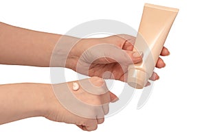 Beige cream tube in woman hands isolated on a white background. Cream swatch on woman hand