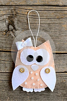 Beige felt owl ornament on an old wooden background. Pretty stuffed owl ornament. Closeup. Vertical photo