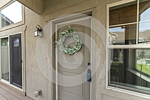 Beige front door with blue lockbox and wreath decoration