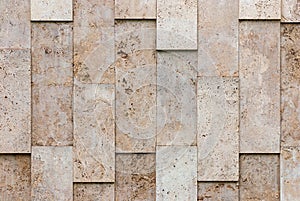 Beige-gray wall of natural textured stone blocks, irregularly arranged