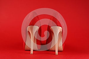 Beige high heels red shoes close up on red background