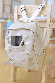 Beige kid backpack hanging on a chair