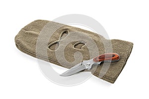 Beige knitted balaclava and knife on white background