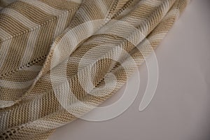 Beige knitted blanked with white stripes.flat lay