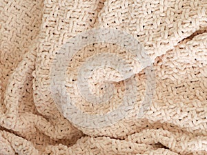 Beige knitted plaid close-up. Background. Creases on soft surfaces