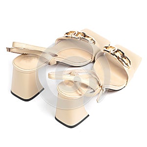 Beige leather women's sandals with a gold chain and a beige weap with a thick heel with a blunt toe on a white