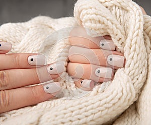 Beige Nails with dots nail desine holding knitted wool