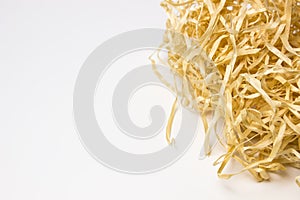 Beige nest of a wooden bird made of paper shavings with quail eggs on a white background with a place for text and inscriptions.