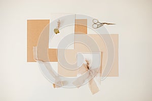 Beige pastel mock up composition of paper envelopes with ribbons, herb. scissors, cut out handmade jobbing. Top view.