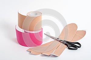 Beige and pink tapes for fixing muscles during sports and after injuries on a white background with scissors. Kinesiological