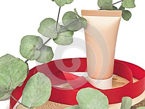 Beige plastic cosmetic tube on a white background with green leaves