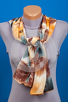 Beige scarf on mannequin isolated on blue background.