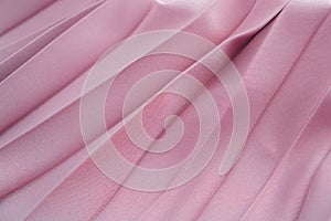Beige silk or satin fabric folded background. Luxurious fabric cloth fold glamour background. Tender and elegant pink silk