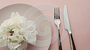 Beige table setting with peony flowers on plate and silverware for luxury dinner party, wedding or birthday celebration