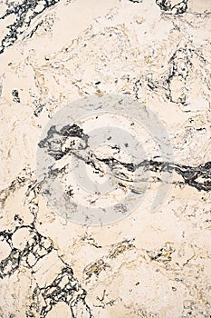 Beige texture of a marble surface with black streaks close-up.