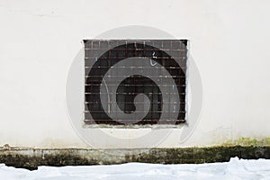 Beige wall with a square window behind a thick rusty old grate for background