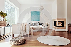 Beige and white textiles and a modern spherical pendant light in a sunny, tranquil living room interior with natural decor. photo