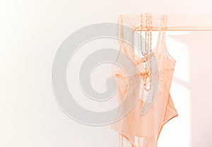 Beige woman`s bodysuit lingerie hanging on mirror