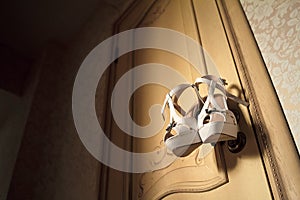 Beige women`s shoes on the door handle, wedding photo