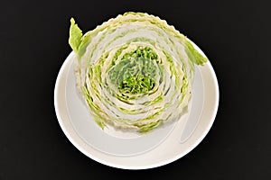 Beijing cabbage on a black background. Permanent manager of fresh, dietary green and white Peking cabbage. In the shape of a