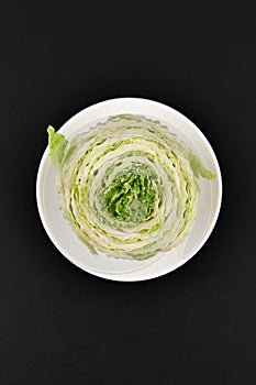 Beijing cabbage on a black background. Permanent manager of fresh, dietary green and white Peking cabbage. In the shape of a