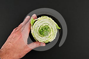 Beijing cabbage on a black background. Permanent manager of fresh, dietary green and white Peking cabbage. In the shape of a