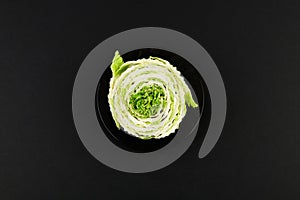 Beijing cabbage on a black background. Permanent manager of fresh, dietary green and white Peking cabbage. In the shape of a