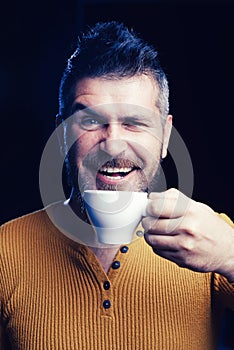 Being in coffee mood. Happy hipster drinking coffee in the morning. Bearded man smiling with coffee cup for breakfast