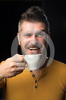Being in coffee mood. Happy hipster drinking coffee in the morning. Bearded man smiling with coffee cup for breakfast