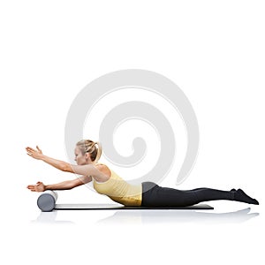 Being fit gives her piece of mind. A young woman using a foam roller to workout while lying on an exercise mat.