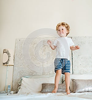 Being a kid is finding joy in the little things. an adorable little boy jumping on the bed at home.
