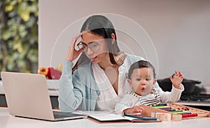 Being a mother is hard work. Shot of a young mother looking stressed while working from home.