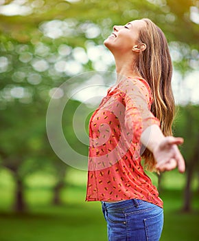 Being outside uplifts the soul. a carefree young woman standing with her arms outstretched in the outdoors.